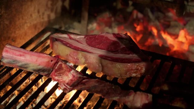 Juicy, raw tomahawk ribeye steak grilling over a hot, flaming charcoal barbecue. Gourmet meat preparation for a delicious barbecue dinner