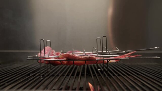 Fresh red snapper grilling in a basket over an open flame. Smoky barbecue process for a healthy and delicious seafood meal in a restaurant kitchen