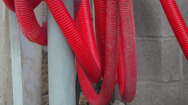 Conduit electrical infrastructure showing red corrugated protective pipes connected to an outdoor utility box on a construction site.