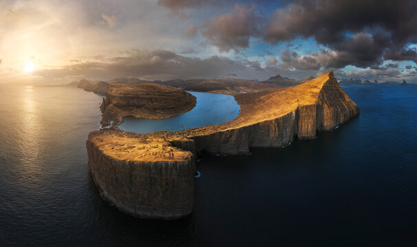 Aerial sunset view of Lake Sorvagsvatn perched above dramatic Atlantic Ocean cliffs at golden hour, Vagar, Faroe Islands.