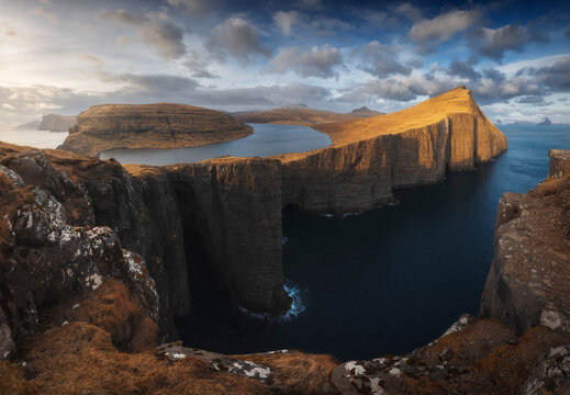 Dramatic panoramic view of Lake Sorvagsvatn perched above the Atlantic Ocean cliffs at golden light, Vagar, Faroe Islands.