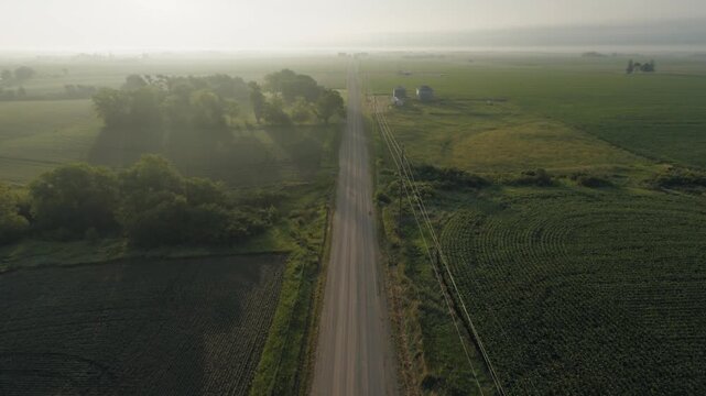 Wide aerial shot of a rural road with a sunrise.