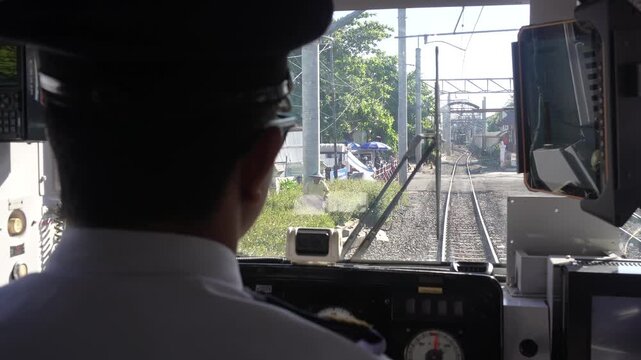 Train driver giving operational hand signal from railway cabin