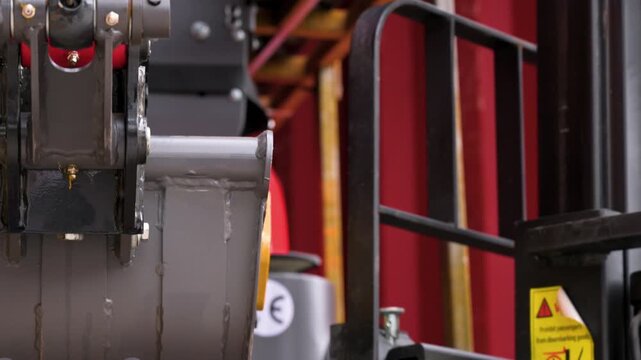 Detail tilt shot of hydraulic cylinders, pistons and hoses on a brand new mini excavator arm mechanical system. High quality 4k footage