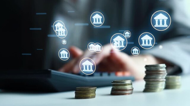 A person is using a laptop to manage finances. There are stacks of coins placed on a desk. Icons of banks appear on the screen, indicating digital transactions.