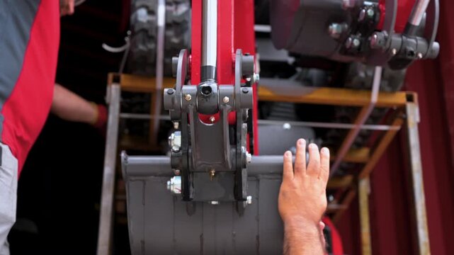 Professional workers manually guiding and checking a mini excavator digging bucket while unloading it from a container. High quality 4k footage