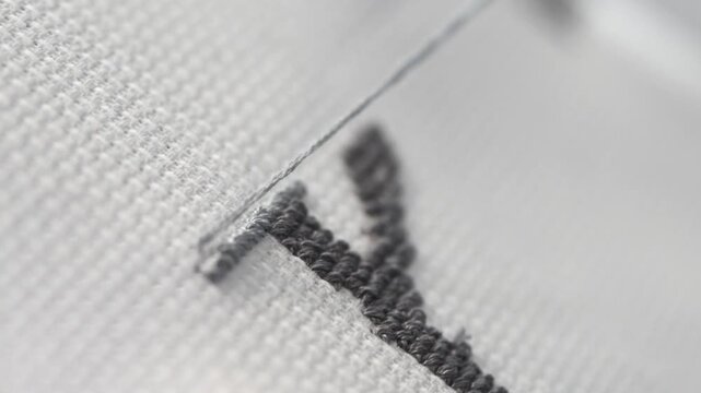 Close up detailed process of black cross stitch embroidery on white fabric with fine needlework