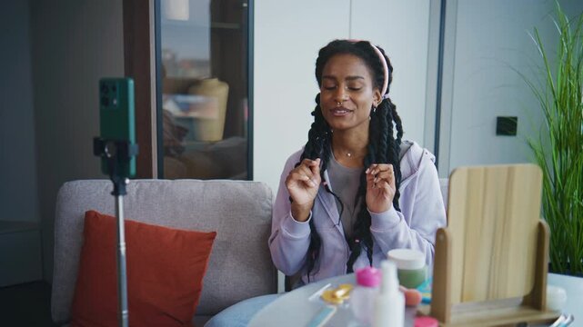 Woman talks about skincare in a bright room during the day while using a smartphone for a video session