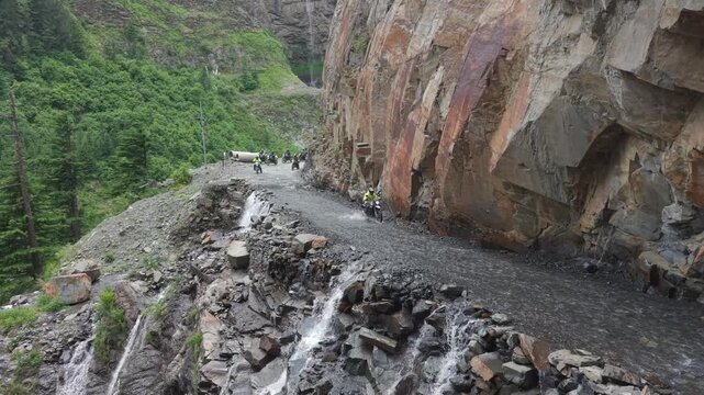Adventure Motorcyclists Crossing Waterfall Cliff Road in Ladakh India