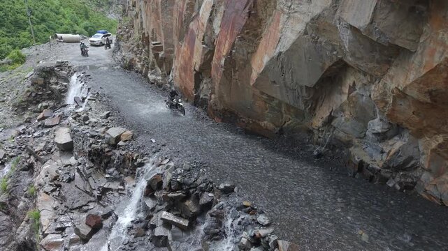 Adventure Motorcyclists Crossing Waterfall Cliff Road in Ladakh India