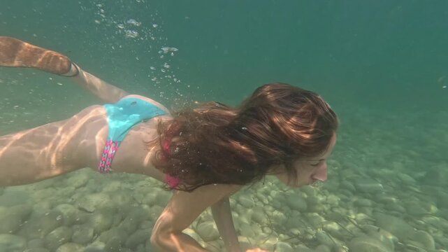 Mujer buceando en apnea de lado a la c&aacute;mara bajo el mar