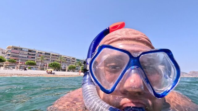 Primer plano de hombre con snorkel saliendo a la superficie