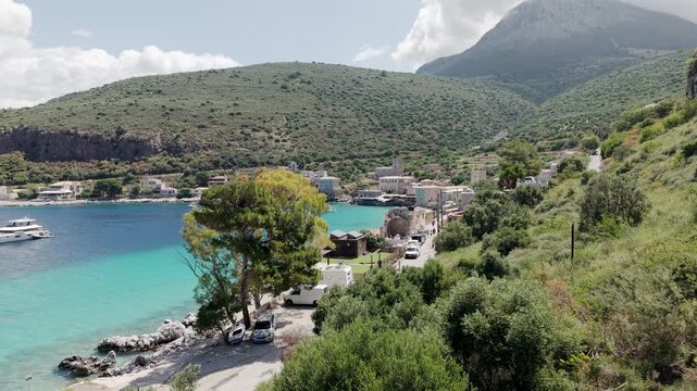 Mediterranean mountains flora, scrubs, drought resistant aromatic vegetation of thyme, rosemary, sage, and oregano, Limeni village on turquoise water, old stone built houses on a sunny day, Drone shot