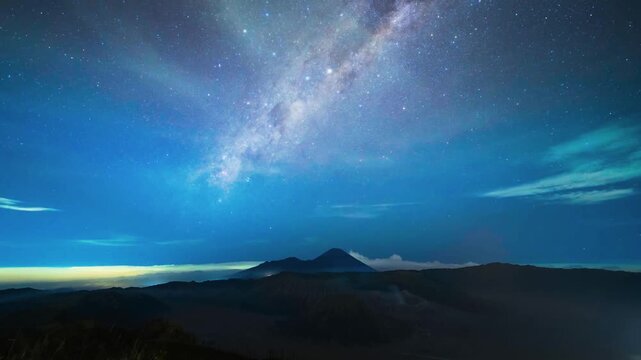 A breathtaking timelapse sequence tracking the vibrant Milky Way galaxy as it arches over the dramatic, dark silhouette of Mount Bromo.