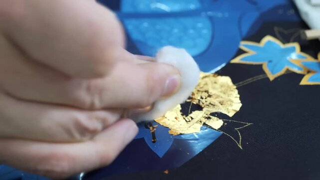 Cotton swab gently rubs away residue from a blue floral pattern featuring a maple leaf motif