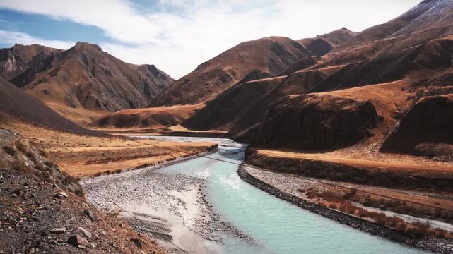 Scenic Rugged Mountain Valley with Turquoise River and Gravel Road during Autumn in Arid Highland Landscape