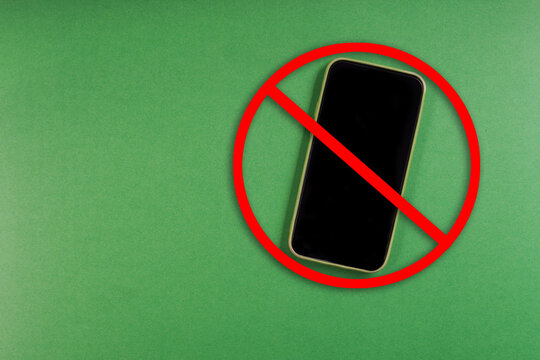 No mobile phone symbol over smartphone on green background with copy space. Digital detox or device free zone concept.