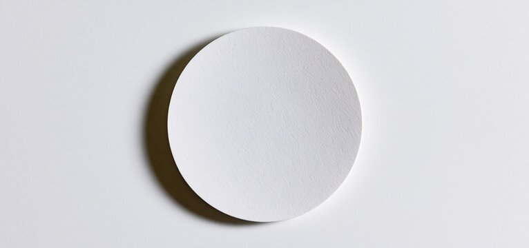 On a pristine white background, a simple round paper coaster designed for drinks and branding.