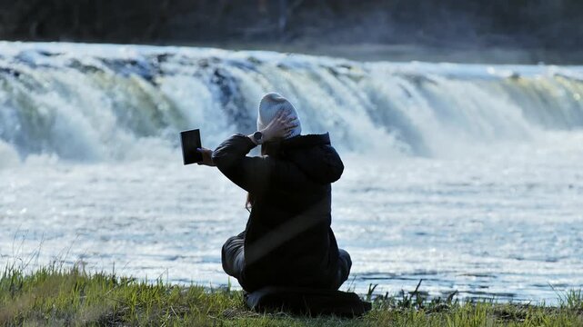 Traveler taking selfie with foldable smartphone, Ventas Rumba waterfall, spring