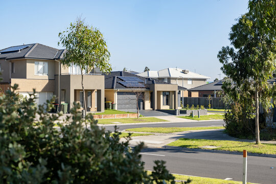 A quiet suburban street features a row of modern houses, neat nature strips and young eucalyptus trees line the asphalt road. a residential estate in Melbourne's outer suburb, Australia