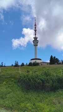 television tower on top of praded mountain with moving clouds