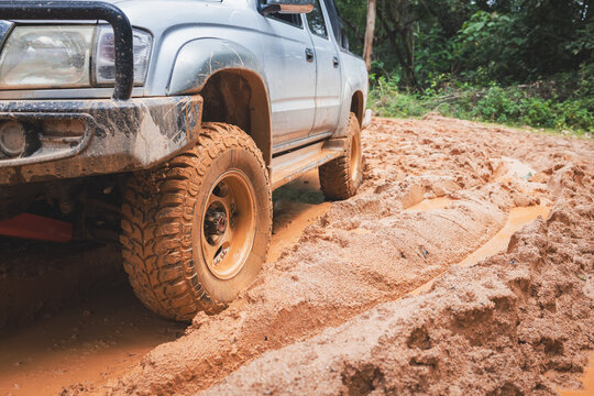 Aggressive mud tires gripping a wet offroad trail as the wheels throw mud in every direction. 4x4 truck, wheel spin, off-road adventure, overlanding, rough terrain, outdoor exploration.