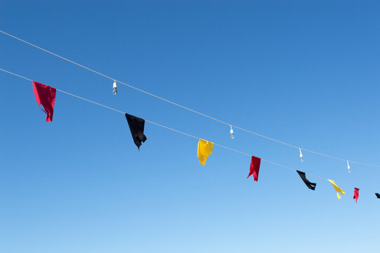 Colorful festive pennant flags hanging against a clear blue sky with copy space