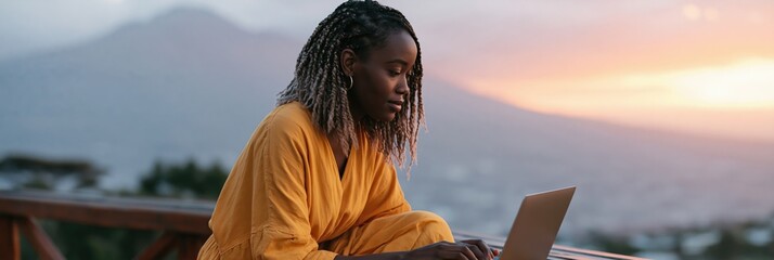 Fototapeta premium Young woman using laptop outdoors at sunset on balcony with mountain and city view for remote work background and banner design