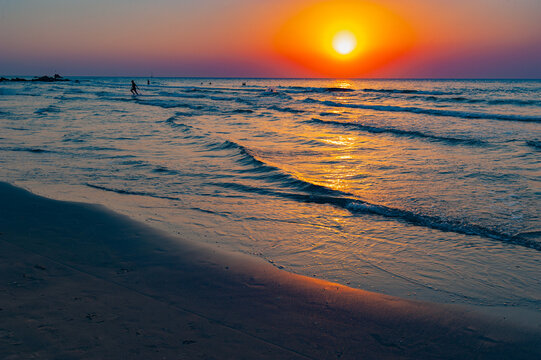 long waves of sunset and the silhouettes of people at sea