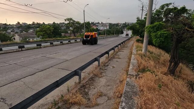 A red big vehicle with large wheels driving to rescue efforts through road after detonation of Kakhovka Hydroelectric Power Station. Consequences of detonation of dam on Dnipro river in kherson city.