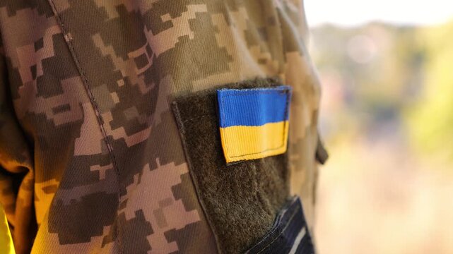 Close up of military blue-yellow chevron on shoulder of soldier at countryside. This emblem embodies the unbreakable spirit and pride of the ukrainian people. Concept of invasion resistance