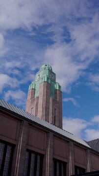 Dramatic clouds moving across the sky above Helsinki city center, with the historic Helsinki Central Railway Station clock tower and urban buildings in the foreground.
