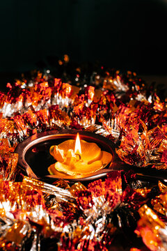 Golden Diwali Diya lamp with flame, floating in a pool of golden tinsel for traditional festival decoration