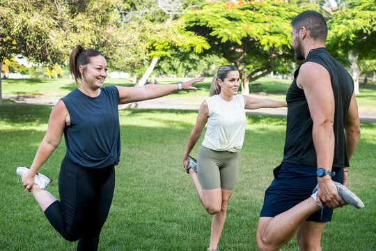 Fitness friends stretching together before an outdoor workout in a park