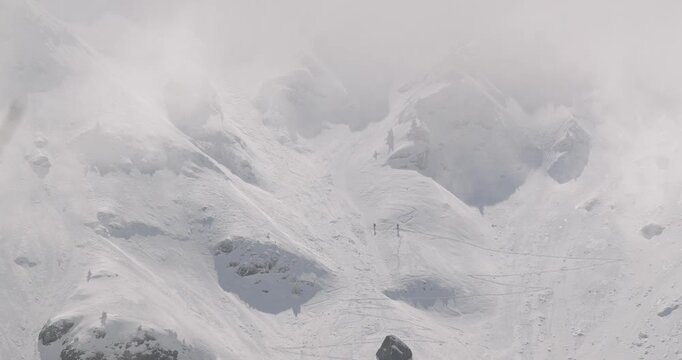 Misty Snowy Mountain Slope with Skiers Descending in Winter