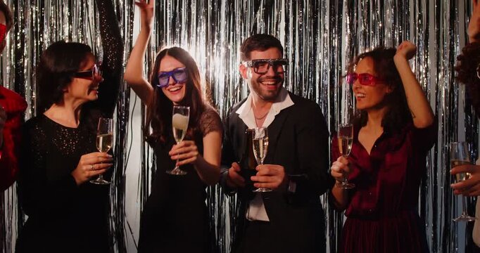 Happy cheerful business team people in suits dancing together celebrating success at corporate party indoors holding champagne glasses. Young friends group having fun at disco. 4k video.