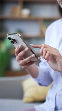 Vertical close up woman hands using smartphone, swiping, scrolling, surfing in social media, reading text message, chatting with friend, browsing on internet. Female shopping online at home. 