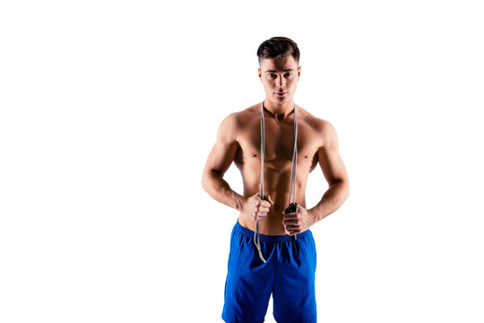 Example of cardio training is using a jump-rope. Handsome sexy nude trainer wearing blue loose shorts is holding a skipping-rope on his shoulders, isolated on grey background, copyspace