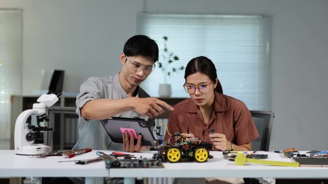 Engineering students collaborating on a robotics project with a tablet and programming an AI car in a modern technology lab