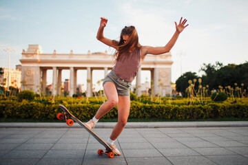 Young woman riding on the longboard skateboard in the park © primipil