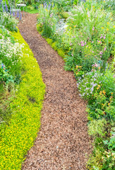 Naklejka premium colorful flowers with rock path leading through a flower garden