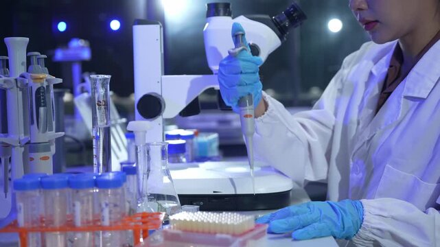 Scientist using a micropipette to transfer samples into a multi well plate for analysis in a laboratory