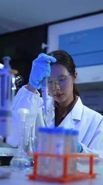 Female scientist pipetting liquid into a test tube during a scientific experiment in a modern laboratory research setting