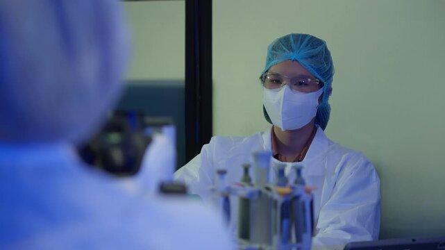Female scientist in protective gear conducting experiment with test tubes in a modern research laboratory