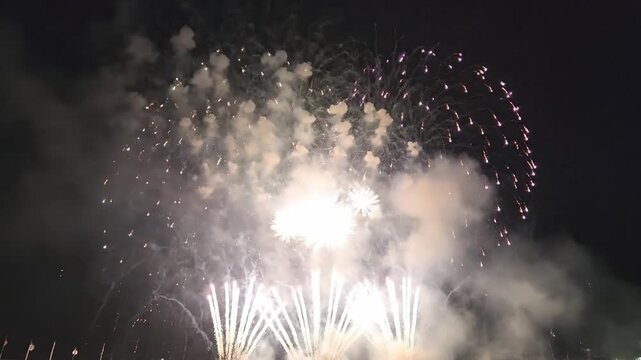 Spectacular fireworks show with vivid colors and smoke trails illuminating the dark night sky