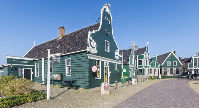 Zaandam, Netherlands - March 22, 2026: Historic green wooden buildings, including the Uurwerk Museum, on a sunny day at Zaanse Schans.