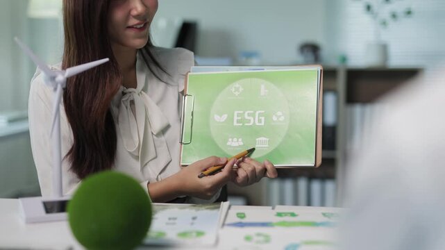 Businesswoman presenting ESG concepts for sustainable corporate development and green energy in a meeting with colleagues