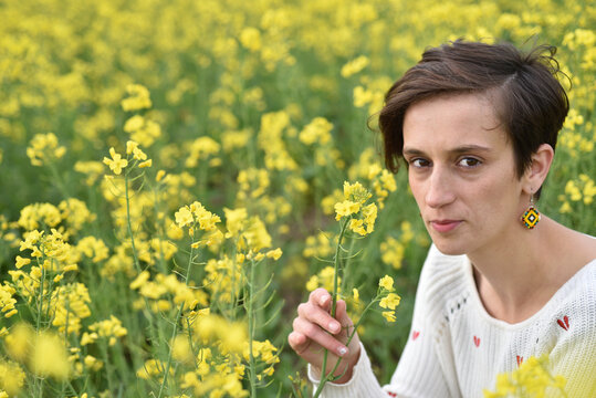 Close up of a woman holding a yellow canola flower