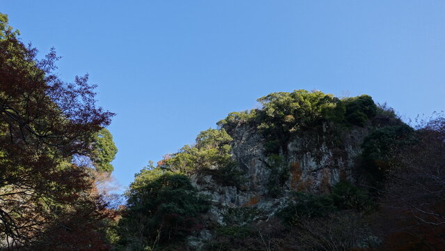 澄み渡る秋空の下にそびえ立つ険しい断崖と樹木