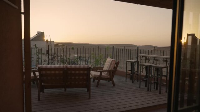 Sunset over desert balcony with lounge chairs and benches overlooking landscape. Beautiful orange warm colors as camera slowly moves in. Romantic and peaceful serene natural view. Vacation or holiday